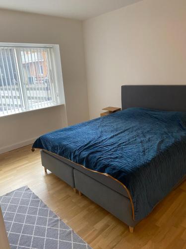 a bedroom with a bed with a blue comforter and a window at Lovely apartment in Vejle C in Vejle