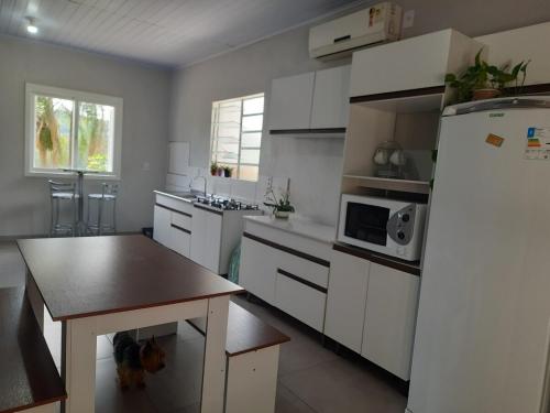 eine Küche mit einem Kühlschrank und einem Tisch darin in der Unterkunft Casa Finger 800m do Centro e do Núcleo de casas Enxaimel anfitriões residem ao lado in Ivoti