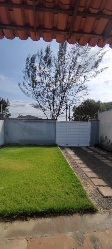 a yard with a white fence and a tree at Casa, Perto de Praias, Shoppings e Valparaíso in Maioba