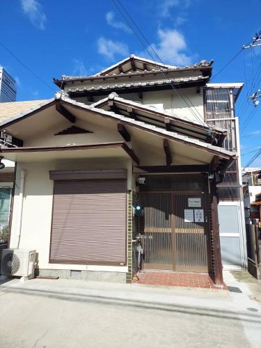 a white house with a brown garage door at りんくう館笠松 関西空港 in Sano