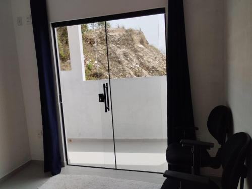 een glazen deur met een raam in een kamer bij Suíte 3 Centro São Thomé das Letras in São Thomé das Letras