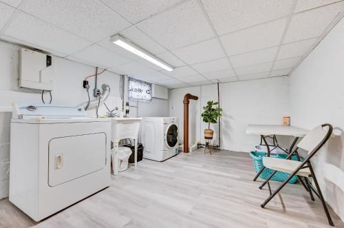 een wasruimte met witte apparaten en een tafel en stoelen bij The Hamilton Elm in Teaneck
