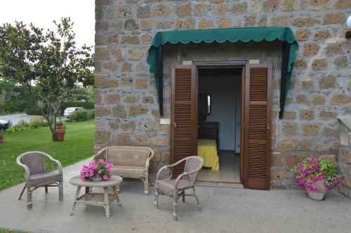 a patio with chairs and a table and a bedroom at Agriturismo I Due Casali in Vetralla