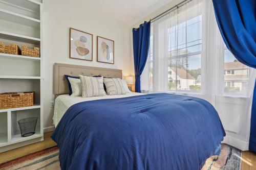 een slaapkamer met een blauw bed en een raam bij The Hamilton Elm in Teaneck