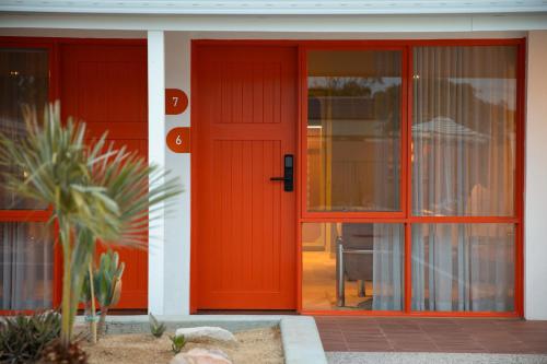 an orange front door of a house with a palm tree at The Monty in Anglesea