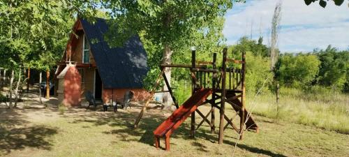 ein Spielplatz vor einem Haus mit einem Gebäude in der Unterkunft Alpinanas in Arroyo de Los Patos