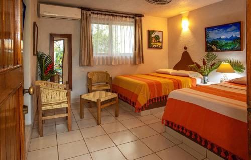 埃斯孔迪多港Hotel Zandoyo Bed & Breakfast的有两张床和一把椅子的酒店房间