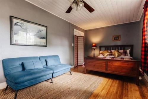 a living room with a blue couch and a bed at Walk to UT Moody Center, 2025 Traveler Award Winner, Magic Tree House in Austin