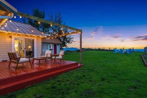 een huis met een terras met stoelen en verlichting bij Marbella Lane Wave HS w EV Charger Oceanfront in San de Fuca