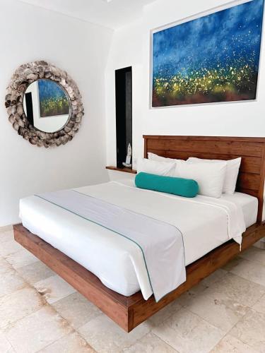 a bedroom with a large bed with a painting on the wall at Kamil Villas in Seminyak