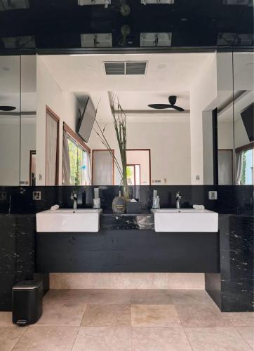 a bathroom with two sinks and two mirrors at Kamil Villas in Seminyak