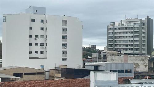 een groep hoge witte gebouwen in een stad bij Apartamento 3 Quartos Praça Cel Tibúrcio Barra in Muriaé