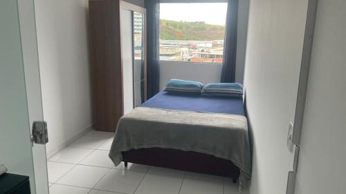 een kleine slaapkamer met een bed en een raam bij Apartamento 3 Quartos Praça Cel Tibúrcio Barra in Muriaé