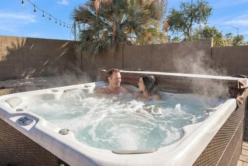 a man and a woman in a hot tub at Sleeps 14 Pool Fire Pit Billiards EV Plug in Mesa