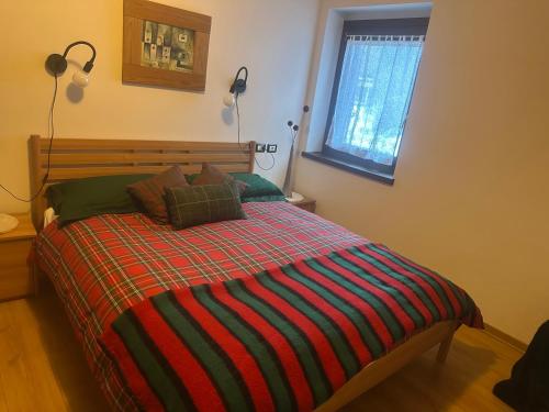 een slaapkamer met een bed met een gestreepte deken en een raam bij Casa Cappuccetto in Imer