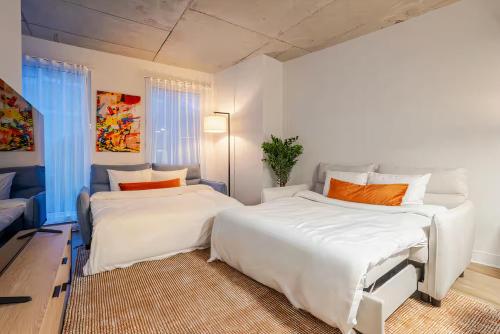 2 letti in una camera con pareti bianche e cuscini arancioni di Charming condo in Rosemont a Montréal