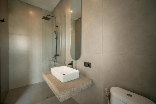 een badkamer met een witte wastafel en een toilet bij Snuggy Shack Villas in Munggu