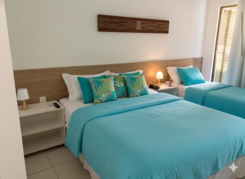 a bedroom with two beds with blue and white sheets at Iloa Studio Alagoas sofisticação de alto padrão in Barra de São Miguel