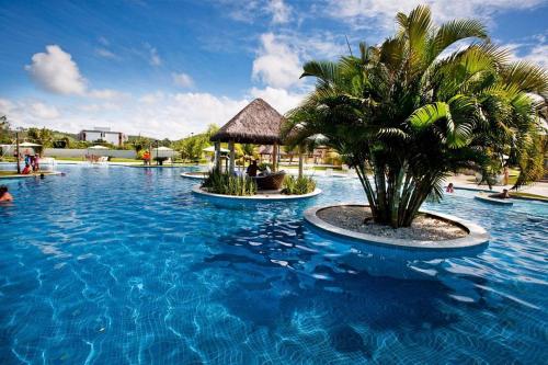 a resort swimming pool with a palm tree and a gazebo at Iloa Studio Alagoas sofisticação de alto padrão in Barra de São Miguel