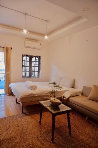 a bedroom with a bed and a couch and a table at KUHA home in Nha Trang