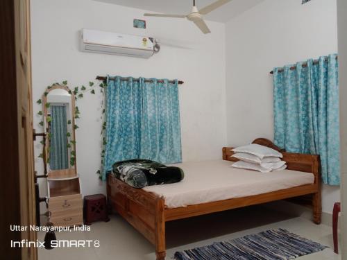 Schlafzimmer mit einem Bett mit blauen Vorhängen und einem Spiegel in der Unterkunft Swpnaneer home stay in Shānti Niketan