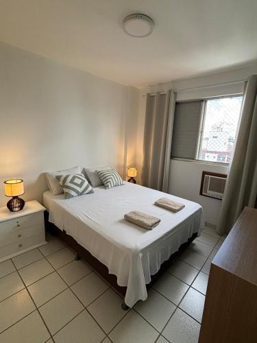 a bedroom with a large white bed with two pillows at Apartamento no centro com ar-condicionado in Piracicaba