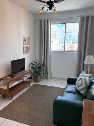 a living room with a blue couch and a tv at Apartamento no centro com ar-condicionado in Piracicaba