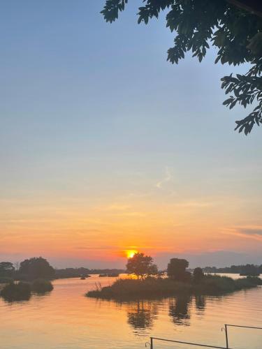 un coucher de soleil sur une rivière avec des arbres dans l'eau dans l'établissement Tena Guest House, à Don Det