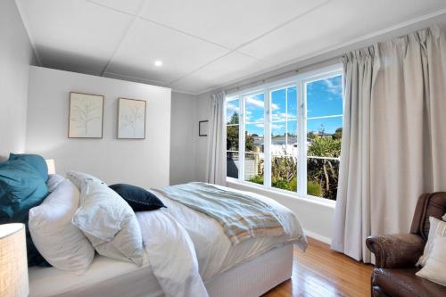een slaapkamer met een bed en een groot raam bij Plum Coastal Cottage in Raumati Beach