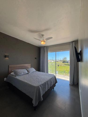 a bedroom with a bed and a large window at Pousada Garden in Tramandaí