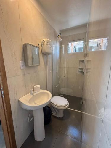 a bathroom with a toilet and a sink and a shower at Pousada Garden in Tramandaí