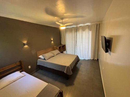 een hotelkamer met twee bedden en een televisie bij Pousada Garden in Tramandaí