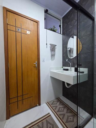 a bathroom with a sink and a wooden door at Sua Estadia Angra - Casa de 2 Quartos no Centro de Angra in Angra dos Reis