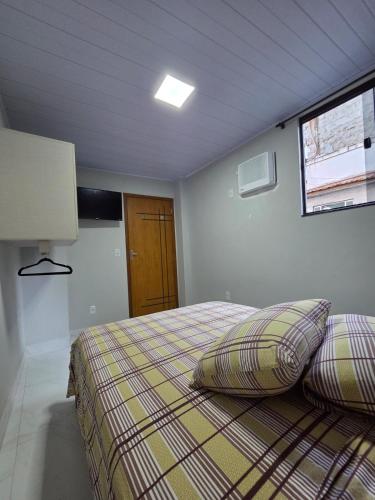 a bedroom with a bed with two pillows and a window at Sua Estadia Angra - Casa de 2 Quartos no Centro de Angra in Angra dos Reis