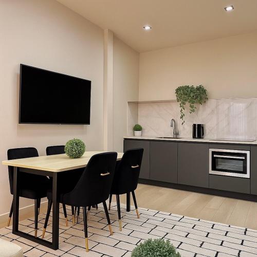 eine Küche mit einem Tisch mit Stühlen und einem TV an der Wand in der Unterkunft Cozy KING Escape Central Free Parking in Pittsburgh