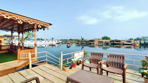 a dock with two chairs and a table with a view of the water at Houseboat Ambassador in Srinagar