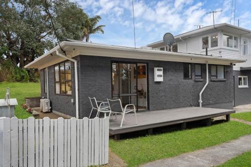 een klein huis met een veranda en een hek bij Henderson Oasis in Auckland