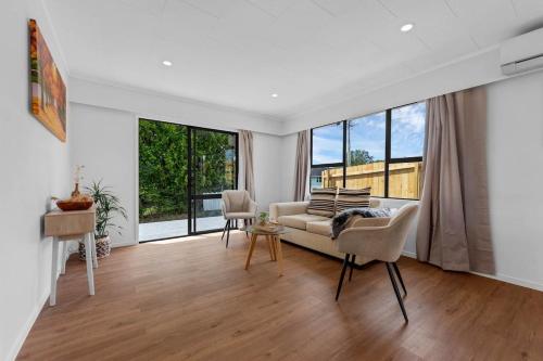 een woonkamer met een bank en een aantal ramen bij Henderson Oasis in Auckland