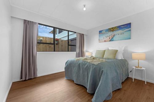 a bedroom with a bed and a large window at Henderson Oasis in Auckland