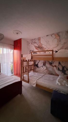 een slaapkamer met 2 stapelbedden en een muurschildering bij Amanecer Costero in Santa Marta
