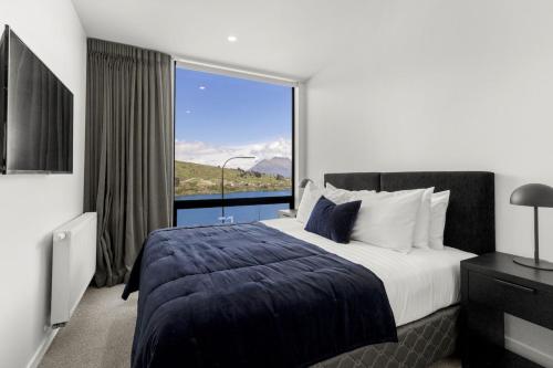 a bedroom with a large bed with a large window at Belle Vue Villa - Stunning Views with Hot Tub in Queenstown