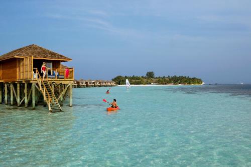 a person in a kayak in the water near a pier at Vilamendhoo Island Resort & Spa in Dhangethi