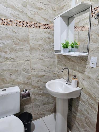 een badkamer met een wastafel, een toilet en een spiegel bij Refúgio à Beira Mar Na Praia da Tartaruga in Rio das Ostras