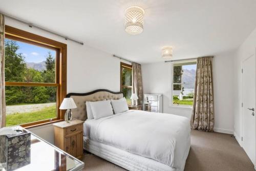 a bedroom with a bed and a large window at Lakeside Bliss Homestead with outdoor spa in Queenstown