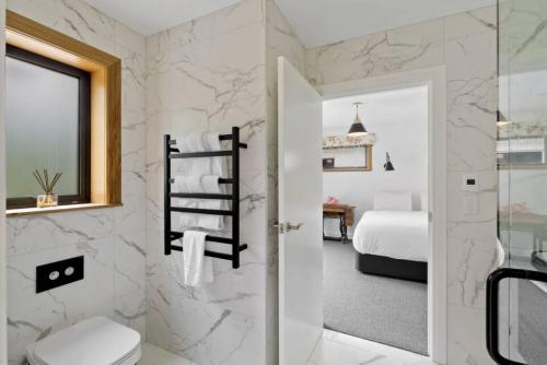 a bathroom with a toilet and a bedroom at Lakeside Bliss Homestead with outdoor spa in Queenstown