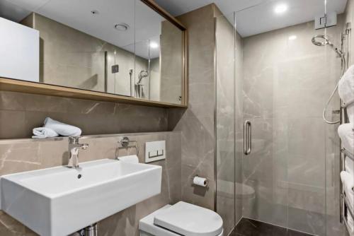 a bathroom with a sink and a toilet and a shower at Mountain Views Penthouse - Apartment 22 in Queenstown