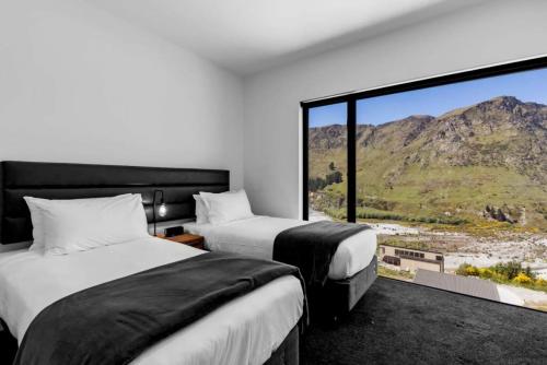 a hotel room with two beds and a large window at Mountain Views Penthouse - Apartment 22 in Queenstown