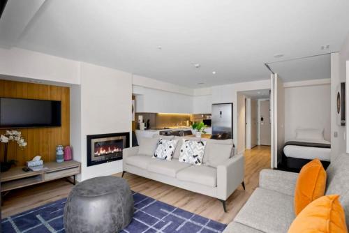 a living room with a white couch and a fireplace at Suki Apartment at the base of Coronet Peak in Queenstown