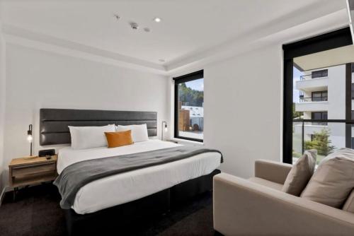 a bedroom with a large bed and a couch at Suki Apartment at the base of Coronet Peak in Queenstown