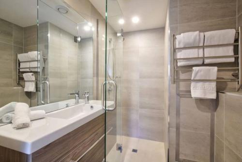 a bathroom with a sink and a glass shower at Rihir Apartment at the base of Coronet Peak in Queenstown